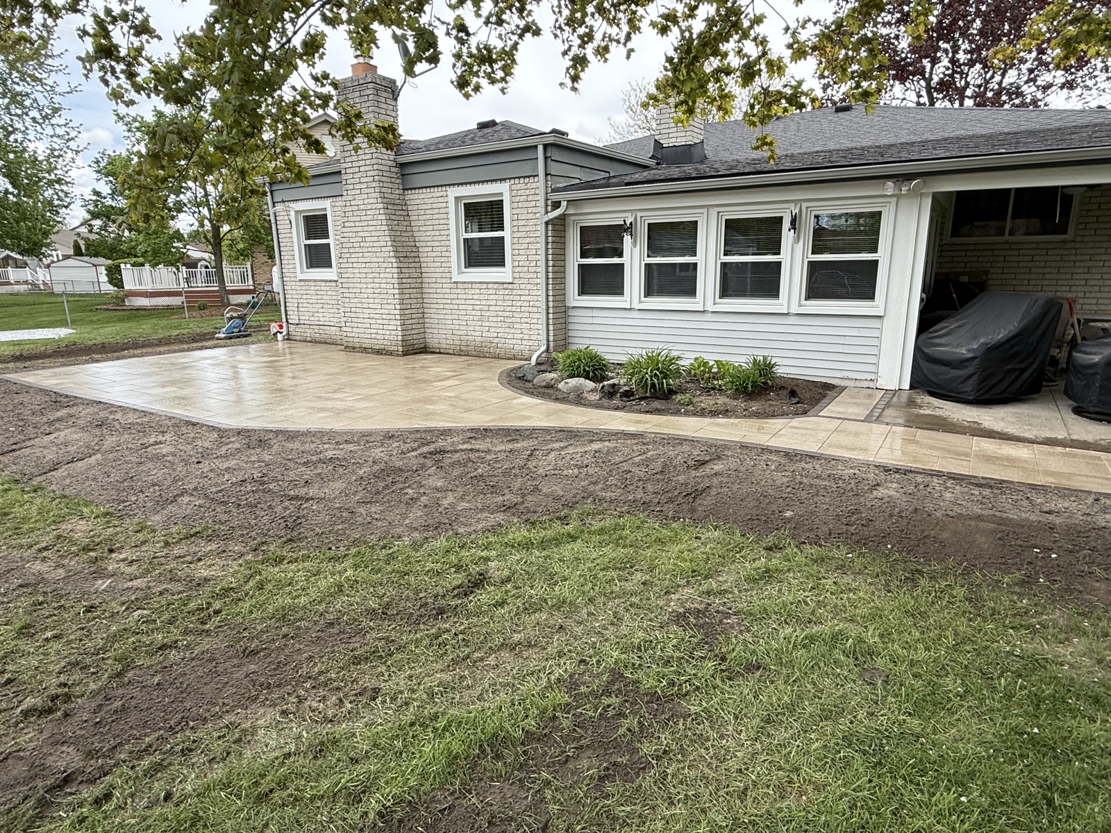 Finished brick paver patio with landscaping bed in Macomb, MI